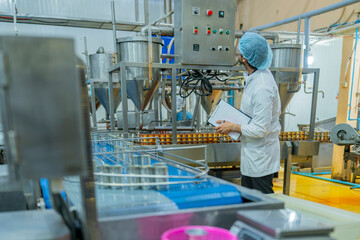 A factory worker inspects advanced machinery in a modern food production facility, ensuring seamless operations and compliance with hygiene and safety standards for efficient manufacturing processes.