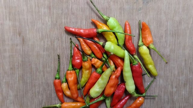 a bunch of cayenne pepper (cabe rawit) with a wooden texture background. This This cayenne pepper is famous for its very high level of spiciness.