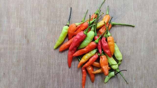 a bunch of cayenne pepper (cabe rawit) with a wooden texture background. This This cayenne pepper is famous for its very high level of spiciness.