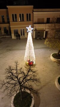 Riprese aeree della piazza di Teulada con l'albero di natale comunale ricco di regali. 