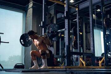 Sporty man bodybuilder or powerlifter exercising deadlift with barbell on cross training in a gym....