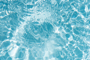 Blue water with ripples on the surface. Defocus blurred transparent blue colored clear calm water surface texture with splashes and bubbles. Water waves with shining pattern texture background.