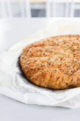 round homemade focaccia bread with rosemary and salt flakes.