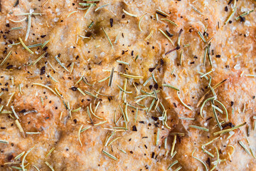 round homemade focaccia bread with rosemary and salt flakes.
