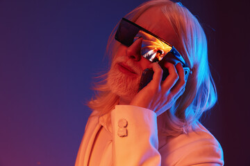 Futuristic portrait of a stylish elderly man using a smartphone against a colorful gradient...