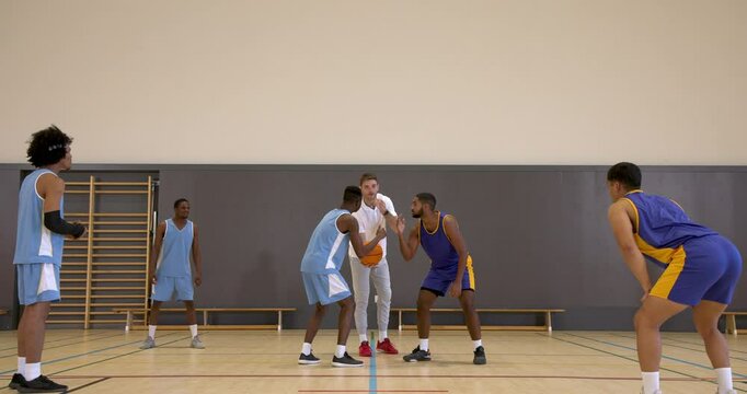 Basketball players in gym preparing for tip-off, focused and ready for action