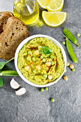 Hummus from green peas in bowl with bread on granite table top