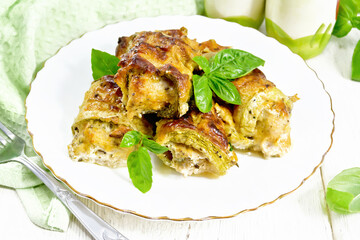 Rolls of zucchini with meat in plate on white board