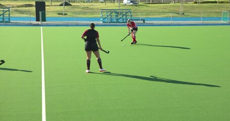 Female hockey player in action on field, skillfully controlling ball - Powered by Adobe