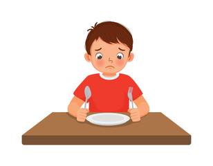Sad little boy feel hungry looking at empty plate
