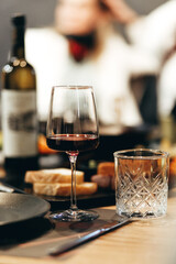 Glass of rich red wine served with cheese plate and fruits on dark wooden background. Appetizers table with wine glasses, rustic style table setting in winery
