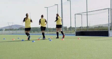 Female hockey players practicing drills on field, focusing on teamwork and skills - Powered by Adobe