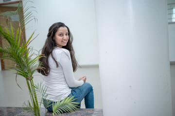 Naklejka premium Indian teen girl working on laptop, sitting on floor with books and study materials,