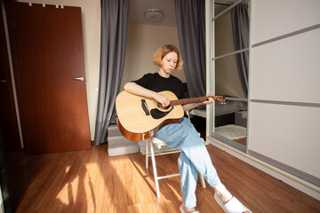 Woman Practicing Acoustic Guitar in Cozy Bedroom, studying musical techniques, exploring music as a...