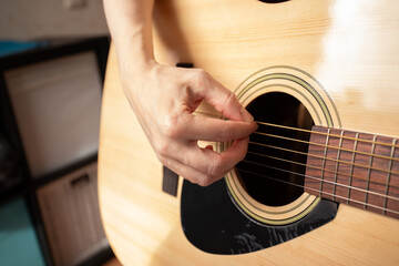 Fototapeta premium Hand Playing Acoustic Guitar Close-Up, person practicing hobby of music, guitarist strumming strings during leisure