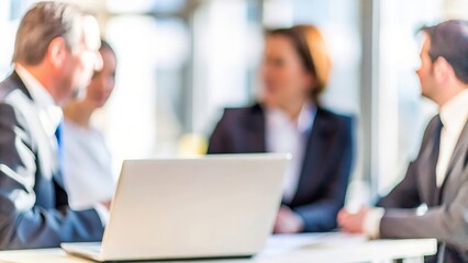 A group of business professionals in a meeting, with the background intentionally blurred.
