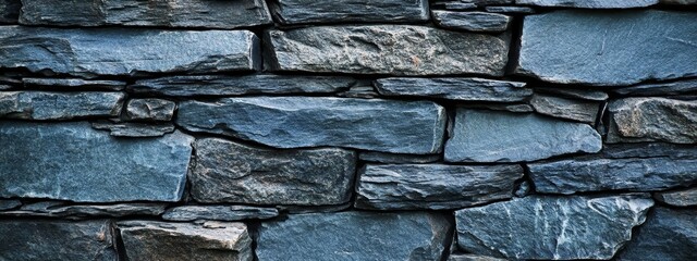 Blue stone wall texture. Close-up of a rustic, uneven stone wall with varying shades of blue and gray.