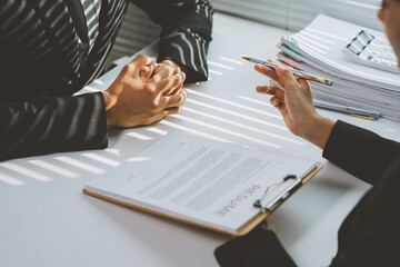 Employer holding a pen in hand is explaining job description to applicant during interview with...