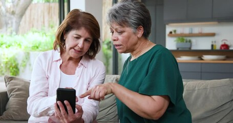 Senior women discussing smartphone content at home, sharing opinions and emotions