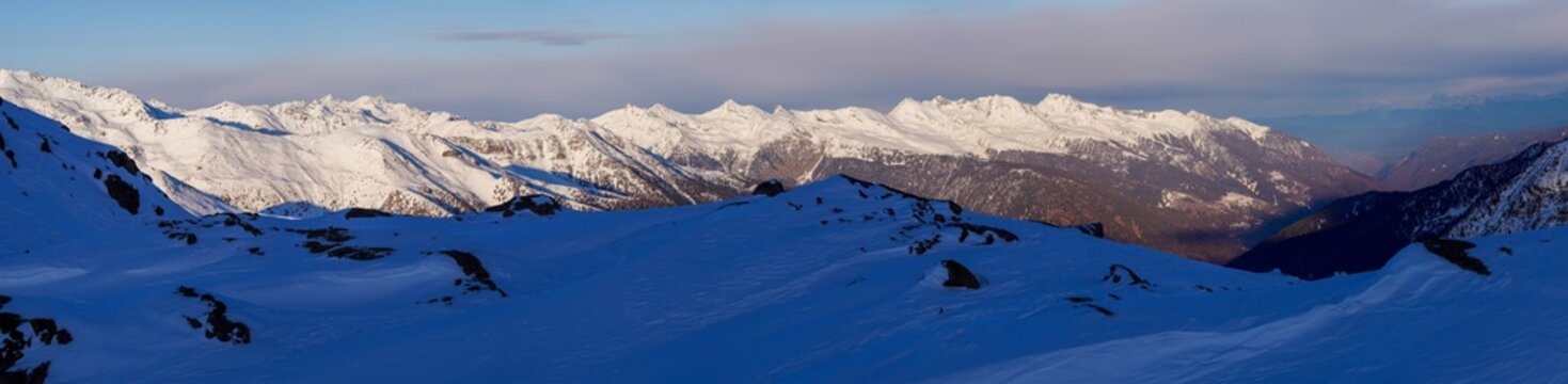 Panoramic view of mountains near Passo Tonale, Ponte di Legno, Italy. Large snowy mountain range under gray cloudy sky. Ski resort landscape on clear sunny day. Mountain ski resort. Snow slope