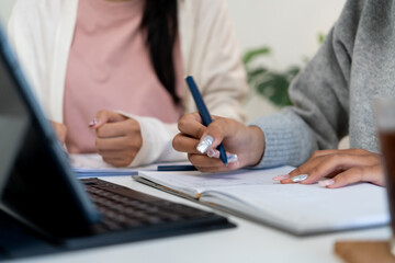 Female higher education student using laptop and studying book in home, Online learning.