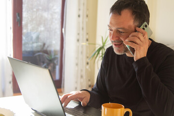 mature man working with pc and phone at home or workplace