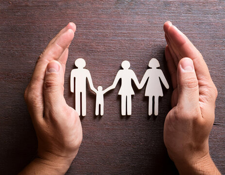 Man holding paper family figures on light blue background, top view. Insurance concept - Powered by Adobe