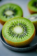 A close-up of a sliced kiwi showcasing its vibrant green flesh, black seeds, and fuzzy brown skin, set against a soft-focus background