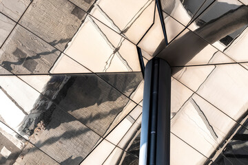 This image captures the intricate reflections on the surface of modern architectural structures, showcasing the play of light and shadows in urban environments.