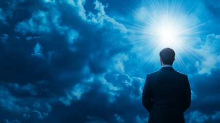 Fototapeta premium Businessman in a suit looks up at the bright sun with hope and inspiration. 