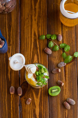 homemade yogurt with kiwi, honey and nuts in a glass on a wooden table