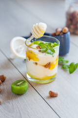 homemade yogurt with kiwi, honey and nuts in a glass on a wooden table