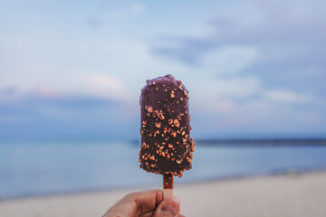 Chocolate ice pop stick with beach blue sky background.
