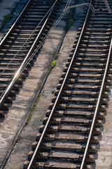 An overhead view of train tracks illuminated by sunlight, featuring intricate reflections along the rails, representing connectivity and movement in urban infrastructure.