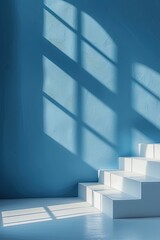 Obraz premium Bright sunlight creates interesting shadow patterns on a blue wall, complementing a white staircase in a minimal, modern space