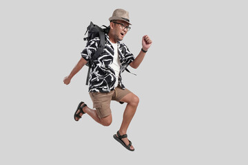 Excited happy young Asian man tourist wearing backpack and glasses jumping pose.