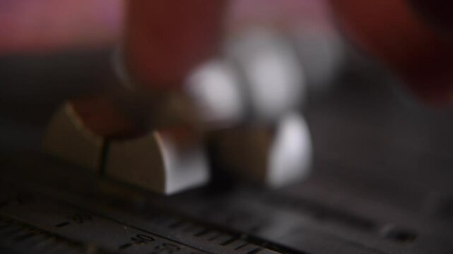 Sound engineer moving faders on the mixing desk during a recording session at the studio