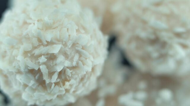 Macro lock follow shot of tasty Raffaello bonbons on a rotating stand, coconut chips, white coco balls, smooth movement 120 fps slow motion video