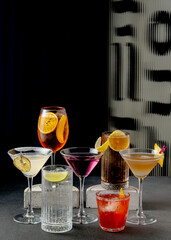 Elegant cocktail assortment in various glasses with citrus garnishes on a dark background.






