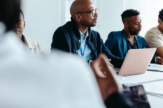 Professional men in a business meeting in a boardroom setting with laptops and documents