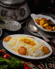 Traditional Middle Eastern saffron rice with dried fruits and crispy potatoes served on a decorative table.