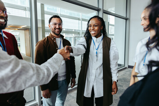 Young businesswoman shaking hands in the office with colleagues around