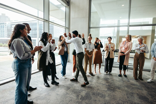 Corporate team celebrating success with high fives during a team building event in a modern office space