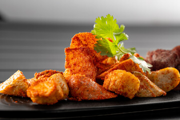 Put fried potato chunks on a black plate