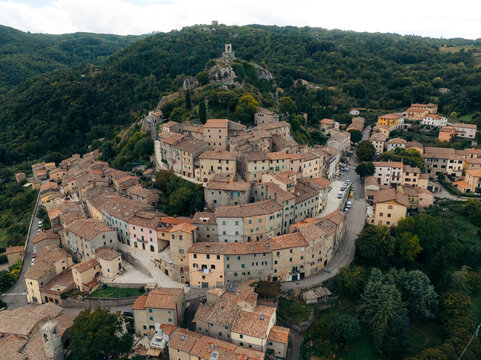 Aerial view of picturesque medieval town with stone buildings and charming rooftops surrounded by hills and forest, Castiglione d'Orcia, Italy. - Powered by Adobe