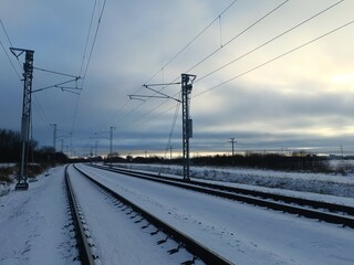 Two way railroad tracks in countryside. Two railway tracks. Sunny day. Countryside. Fields and trees. Snow is laying on ground. 