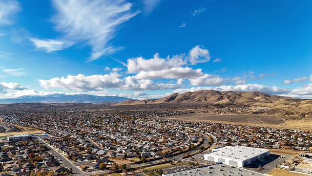 Aerial view of suburban cityscape with expansive neighborhoods and mountain range under a clear blue sky, Spanish Springs, Northern Nevada, United States.