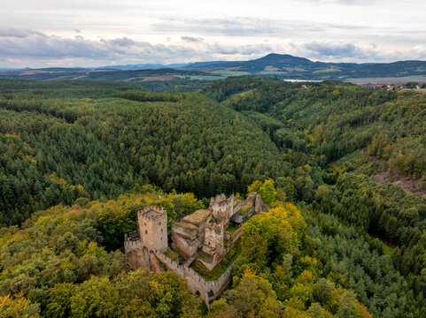 Aerial view of the abandoned medieval castle Burg Helfenburk surrounded by lush autumn forest, Ustek, Czech Republic.