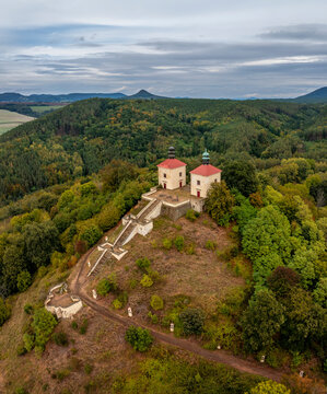 Aerial view of an old church on a hill surrounded by vibrant autumn trees and a tranquil forest, Calvary Ostre, Usti nad Labem, Czech Republic.