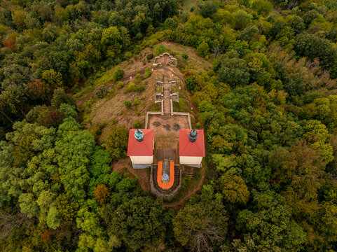 Aerial view of an old church on a hill surrounded by vibrant autumn foliage and trees, Ustek, Czech Republic.